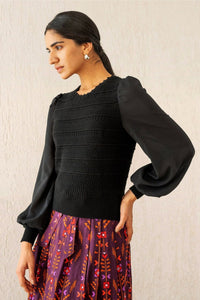 Side view of woman wearing the Rosie knit, featuring hand-crocheted details and viscose georgette sleeves, blending structure with textural complexity.