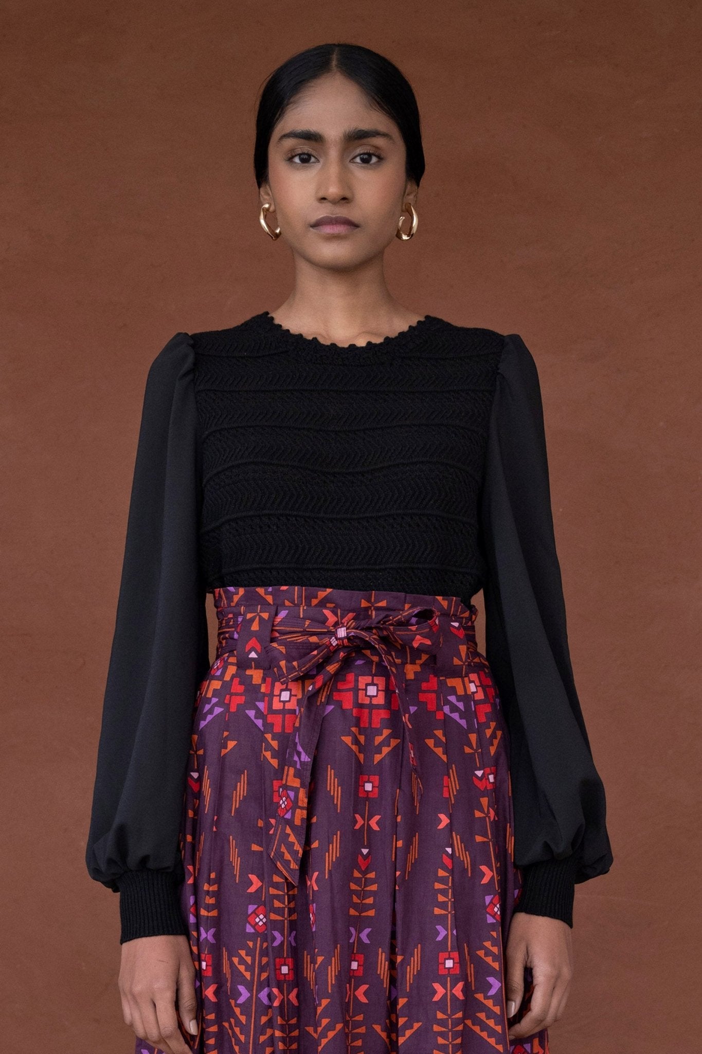 Front view of woman wearing the Rosie knit, featuring hand-crocheted details and viscose georgette sleeves, blending structure with textural complexity.