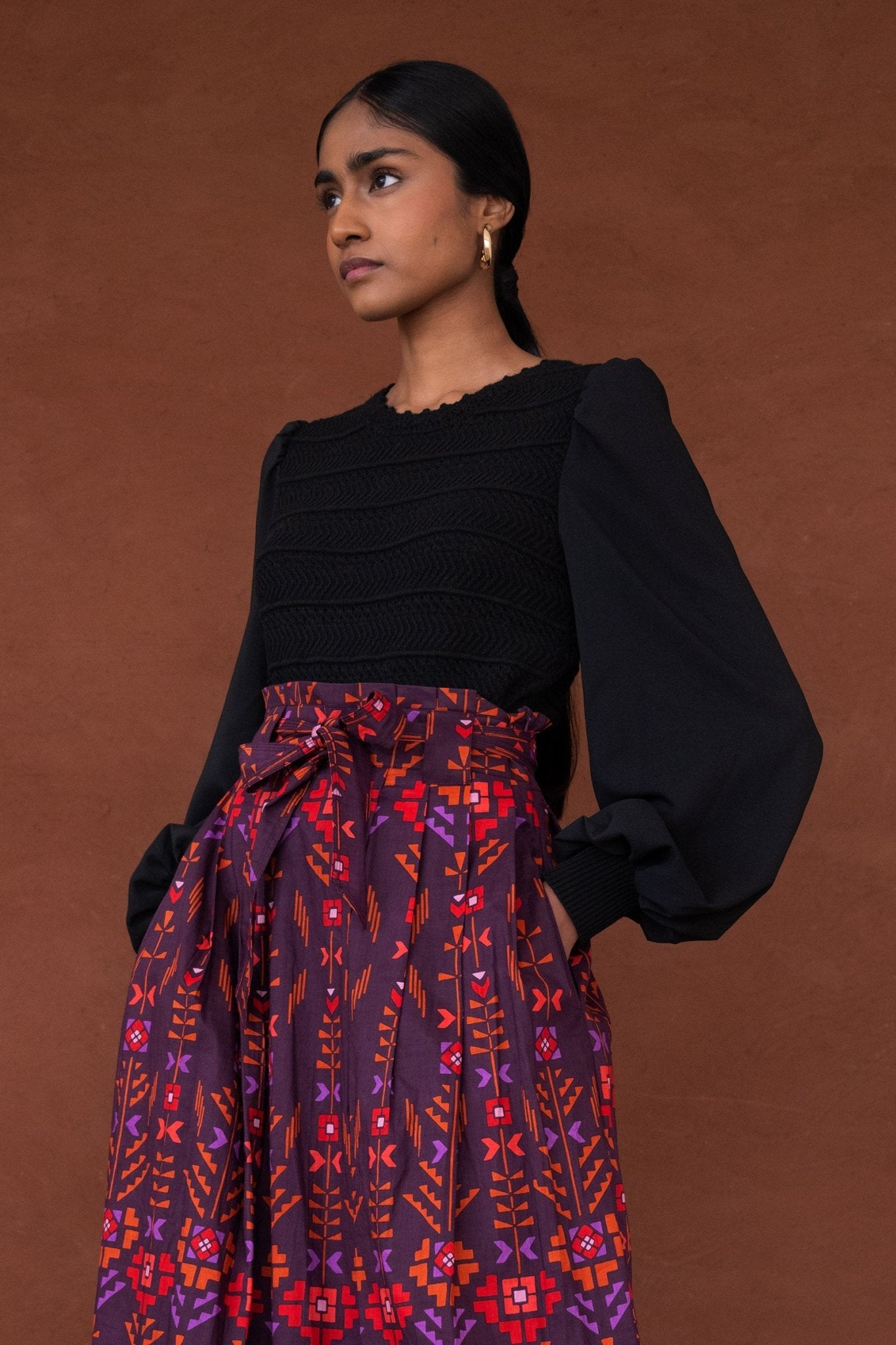 Side view of woman wearing the Rosie knit, featuring hand-crocheted details and viscose georgette sleeves, blending structure with textural complexity.