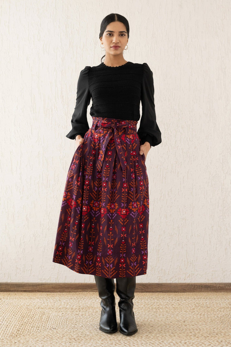 Front view of a woman wearing the Tobias skirt with a paper bag waist, self-tie belt, and pockets in Emilie Deco Cinnamon print, inspired by Austrian Art Nouveau.