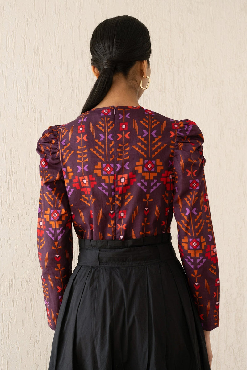 Back view of a woman wearing the Vincent top with soft gathers at the neck and shoulder, featuring a zipper at the back in Emilie Deco Cinnamon print, inspired by Art Nouveau.