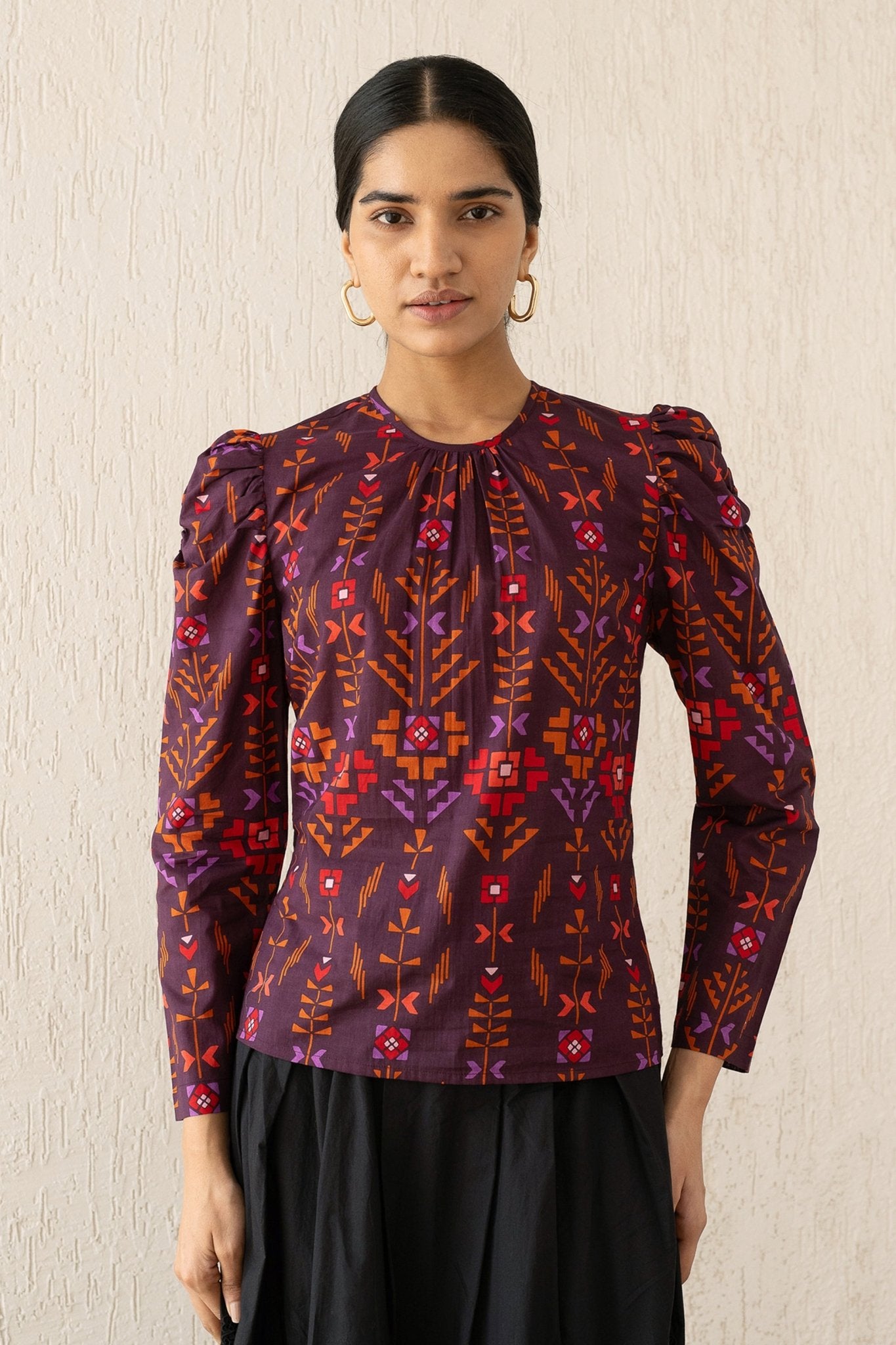 Front view of a woman wearing the Vincent top with soft gathers at the neck and shoulder, featuring a zipper at the back in Emilie Deco Cinnamon print, inspired by Art Nouveau.