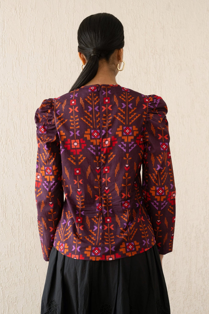 Back view of a woman wearing the Vincent top with soft gathers at the neck and shoulder, featuring a zipper at the back in Emilie Deco Cinnamon print, inspired by Art Nouveau.